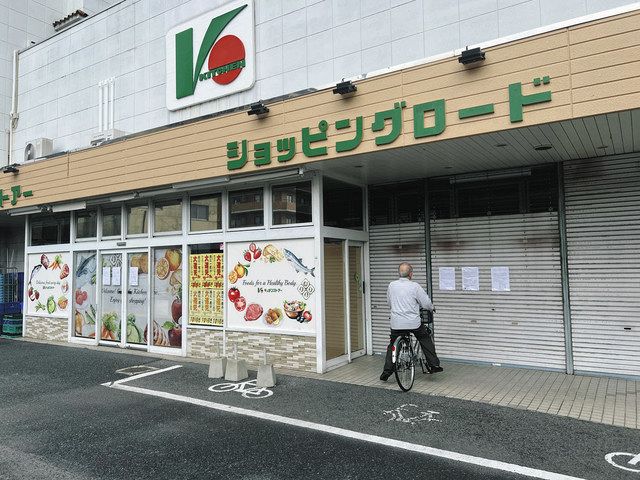 シャッターが閉じた店舗前で営業停止の張り紙に見入る常連客＝足利市で 