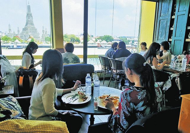 タイ・バンコクで13日、ワット・アルンを望むレストランでタイ料理を楽しむ日本からの旅行者ら