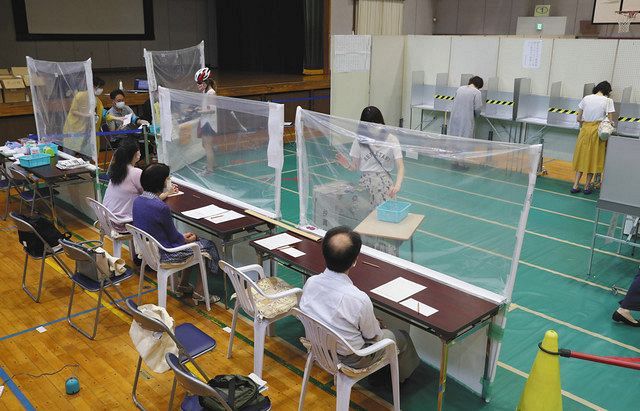 都知事選の投票をする有権者。フィルムの設置や記帳台の間隔を空けるなどの新型コロナ感染症対策が施された＝５日、東京都港区で 
