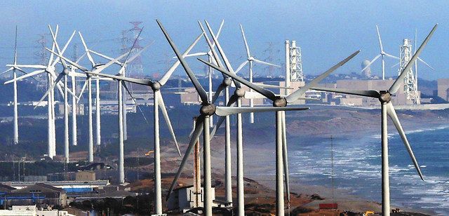 遠州灘海岸沿いに建ち並ぶ風力発電の風車。奥は中部電力浜岡原発＝静岡県掛川市で、本社ヘリ「おおづる」から