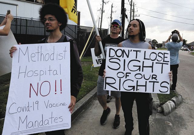 ８日、米テキサス州ヒューストンで、ワクチン未接種の職員約１８０人を停職処分にした病院前で抗議デモをする人たち＝ＡＰ