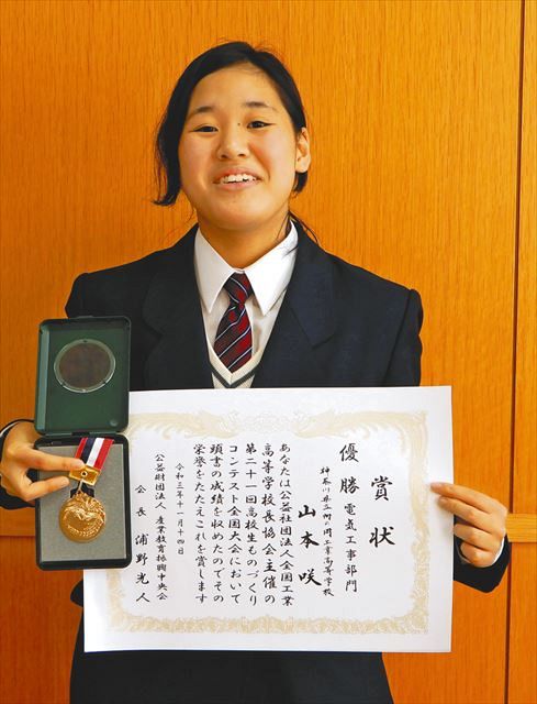 全国大会で優勝した賞状とメダルを持つ山本さん＝川崎市の向の岡工業高校で