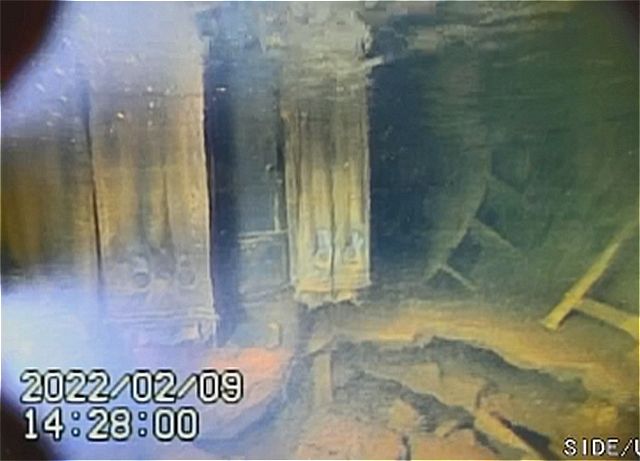 1号機原子炉の格納容器底部の様子。左に見えるのは放射線を遮へいするために配管に巻かれた鉛毛マット。右下には堆積物が見える＝東京電力福島第一原発で（国際廃炉研究開発機構、日立GEニュークリア・エナジー提供）