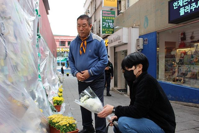 ソウル・梨泰院で28日、事故現場で献花する若者を迎える南仁錫さん㊧＝相坂穣撮影