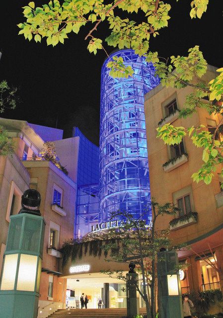 青色にライトアップされたラ　チッタデッラのガラスのタワー＝川崎区で
