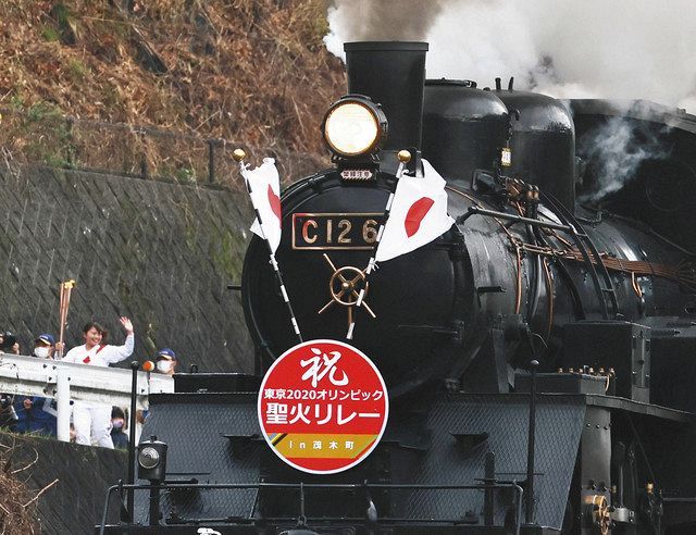 栃木県茂木町で行われた聖火リレーで、並走する真岡鉄道の「ＳＬもおか」号の乗客らに手を振るランナー（左）
