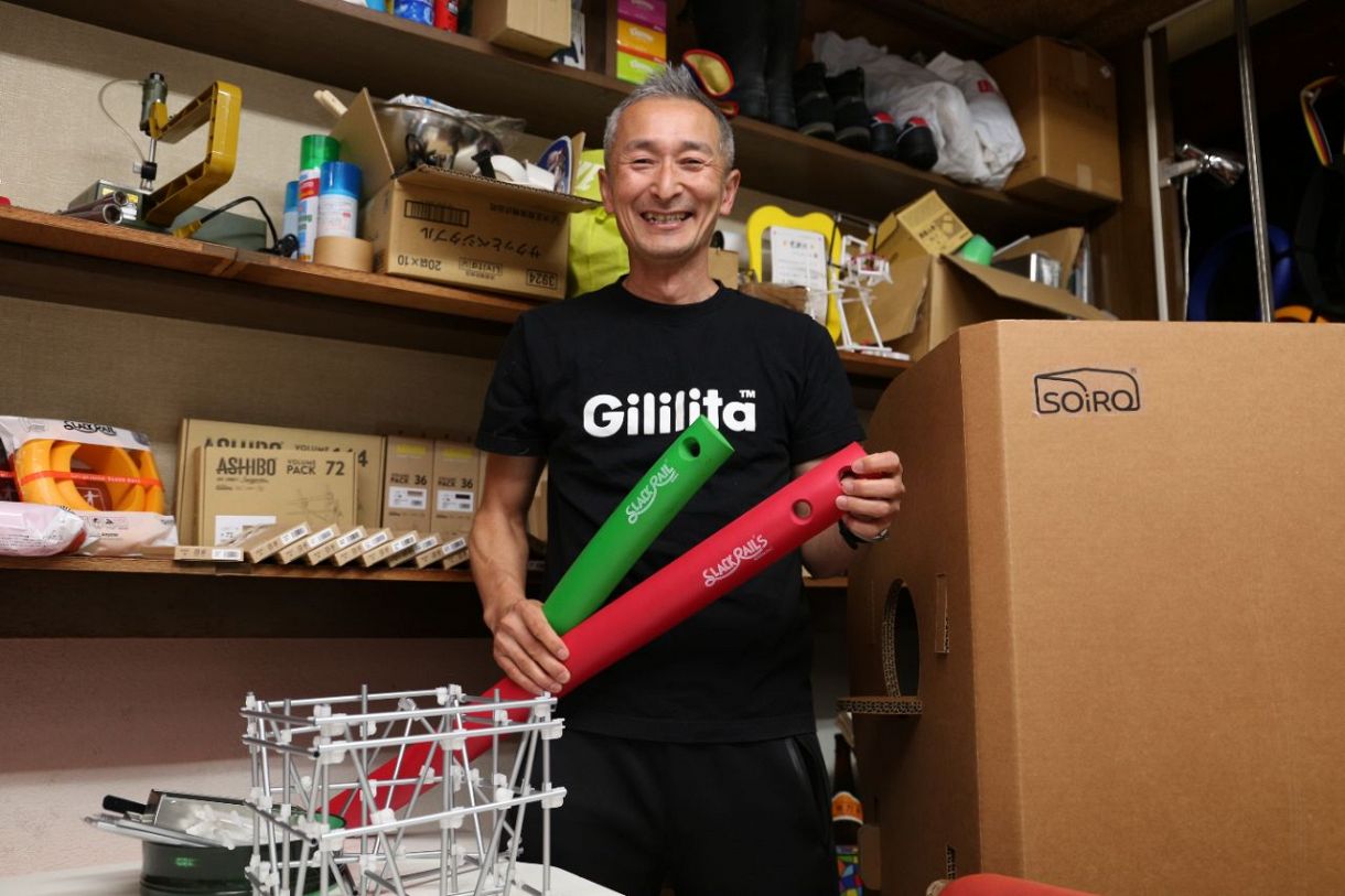 地域の人とおもちゃ開発を続ける高島勇夫さん、手には自慢の「スラックレール」＝東京都北区で