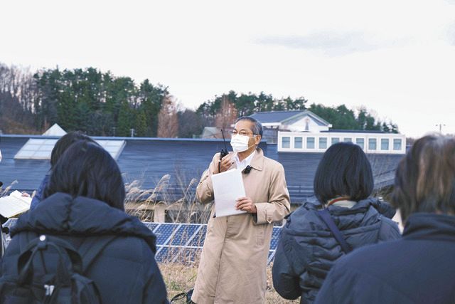飯舘電力が初めて建てた太陽光発電所を前に、ツアーの参加者に説明する千葉訓道さん＝福島県飯舘村で（同社提供）