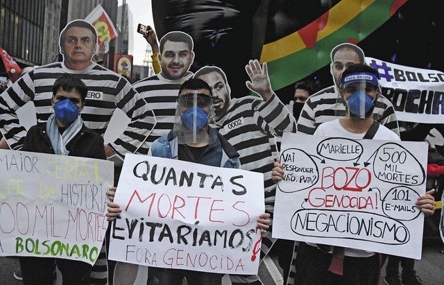 １９日、ブラジル・サンパウロでボルソナロ大統領への抗議のメッセージを掲げるデモ参加者（共同）