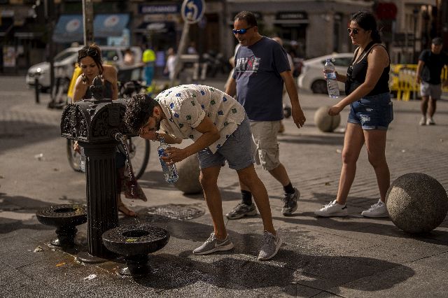スペイン・マドリードの街で猛暑の中、水分補給する男性＝AP