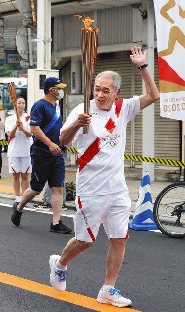 聖火をともしたトーチを掲げて走る武田博知さん＝伊東市で
