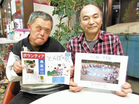とんぼの会の写真集やチラシを持って受章の喜びを語る村川さん（右）と小田さん＝ふじみ野市で
