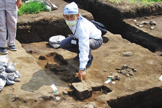 基壇（土台）の外装に使われたとみられる凝灰岩の切り石を指さす市教委職員＝高崎市で 