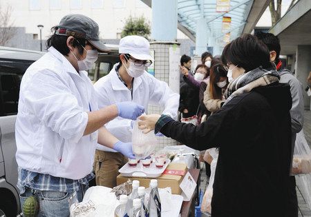 給食休止により納入先がなくなった食材の販売会で、ヨーグルトなどを売る食品メーカーの担当者（左）＝富士宮市で