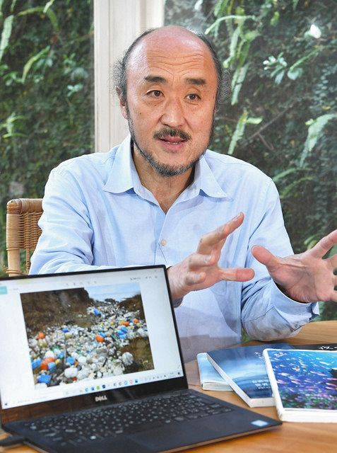 長崎県・対馬に流れ着いたごみの写真を示しながら海の汚染状況を話す自然写真家の高砂淳二さん＝東京都渋谷区で