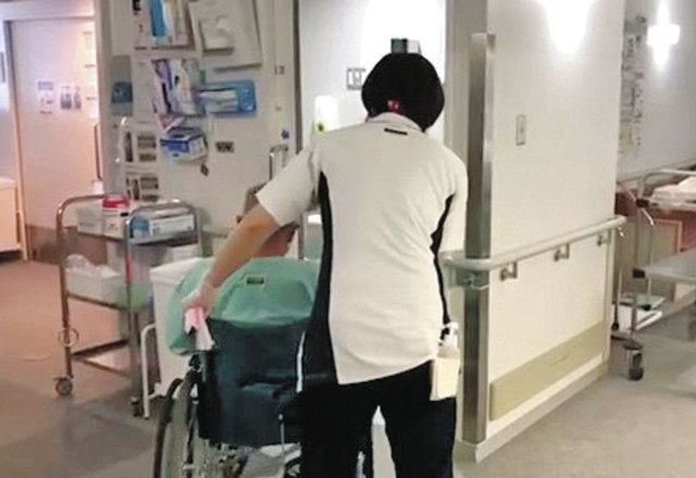 移動に車いすが必要なコロナ患者の対応にあたる病院職員。高齢の患者が増えているという＝東京都品川区の昭和大学病院で（同病院提供）