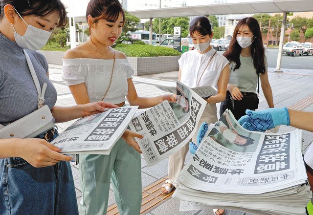 安倍首相が辞任する意向を固め、配られた中日新聞号外を手にする人たち＝浜松市中区のＪＲ浜松駅前で
