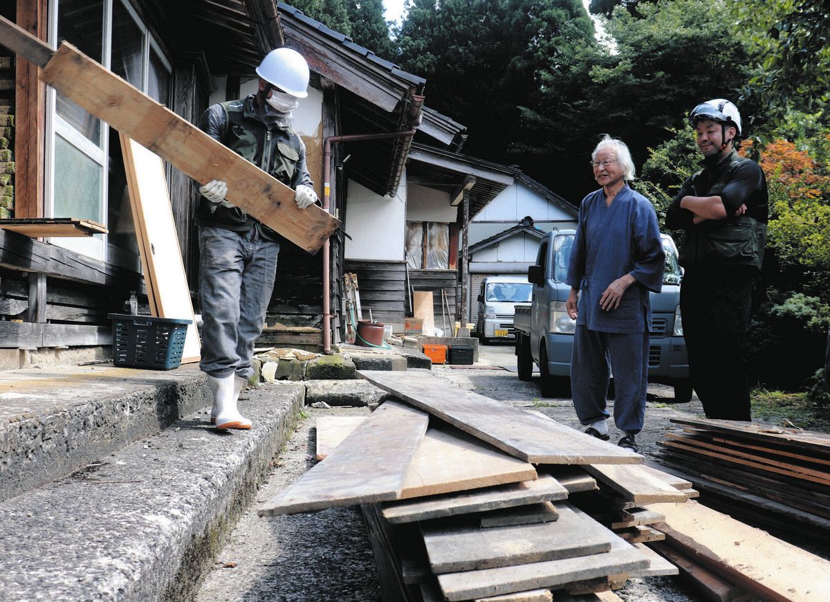 床板などが運び出されるのを見守る「のと復耕ラボ」の山本亮さん（右）と山浦芳夫さん＝石川県輪島市で