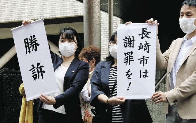 「勝訴」などと書かれた紙を掲げる原告側弁護士ら＝３０日、長崎地裁前で（共同）