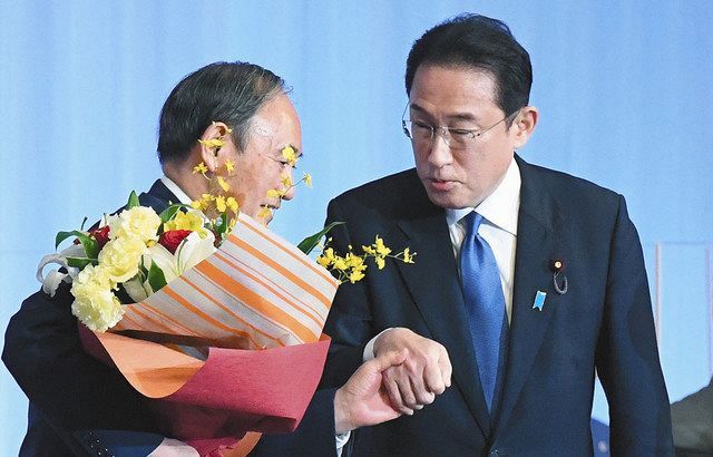 自民党の新総裁に選ばれ、菅首相（左）に花束を贈り握手を交わす岸田文雄氏＝２９日午後３時２３分、東京都内のホテルで