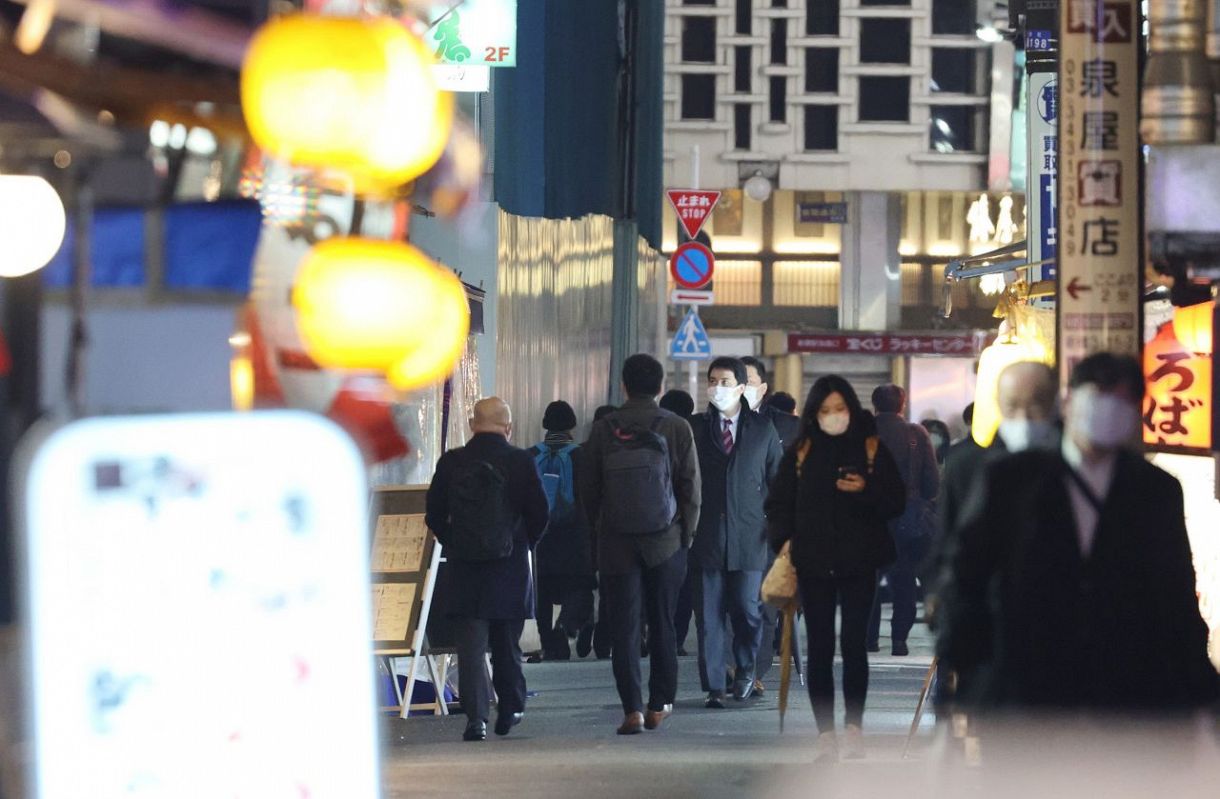 まん延防止等重点措置が解除となった飲食店街をマスク姿で行き交う人たち＝２２日夜、東京・新橋で