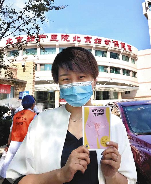 昨年９月、提訴した病院の前にたつ徐さん。手にした冊子には「私の子宮は私のもの」とある＝本人提供