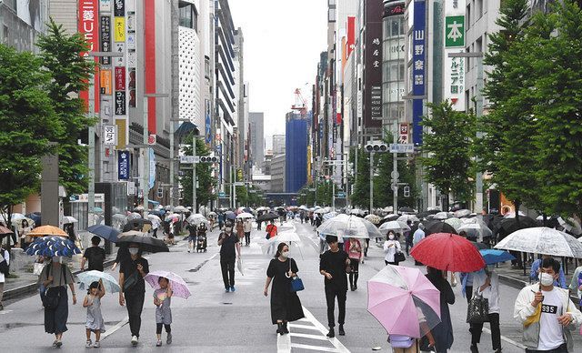歩行者天国が再開した中央通りを傘を差して歩く人たち＝１３日、東京・銀座で
