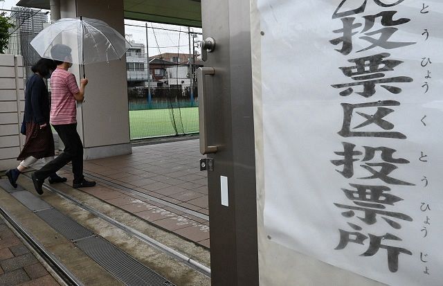 傘を差して投票所に入る有権者ら＝品川区内で