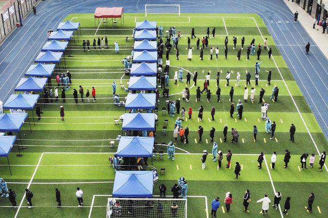 サッカー場に設置されたPCR検査場に並ぶ人々の写真が新華社から配信された＝9日、中国・天津市で（AP）