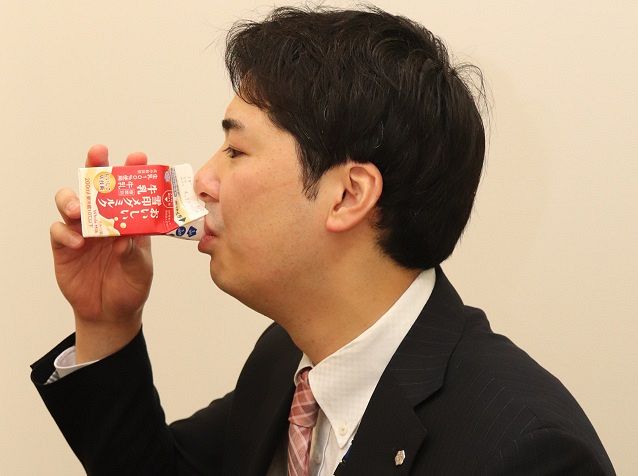 新たに導入したパックでストローを使わずに牛乳を飲む雪印メグミルクの担当者＝東京都新宿区で