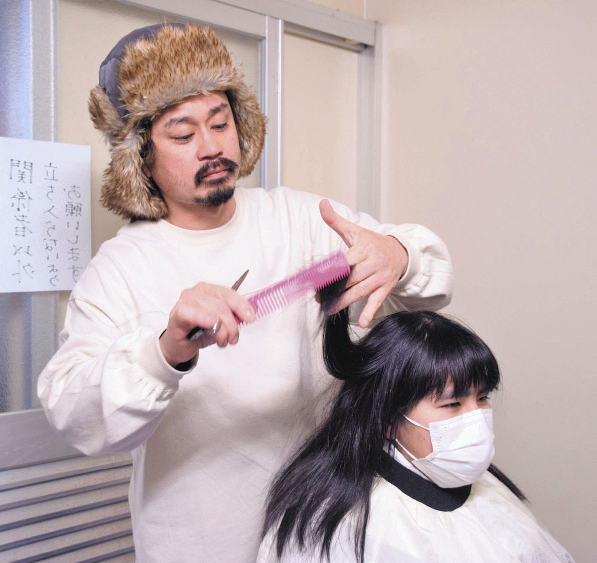 避難者の髪をカットする吉井謙太さん（左）＝石川県珠洲市で
