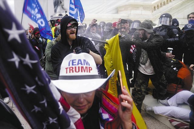 米ワシントンの連邦議会議事堂で、警官隊を押しのけようとするトランプ前大統領の支持者ら＝１月６日（ＡＰ＝共同）