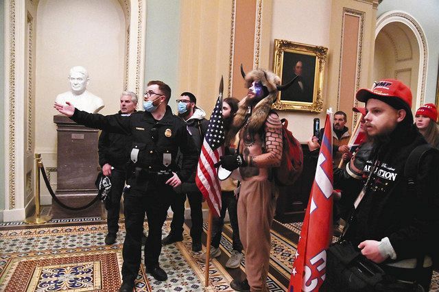 ６日、米ワシントンの連邦議会議事堂に乱入したトランプ大統領の支持者らと話す警察官＝ロイター・共同