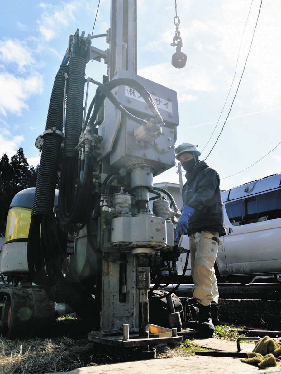 重機で井戸を掘り進める作業員＝石川県輪島市で