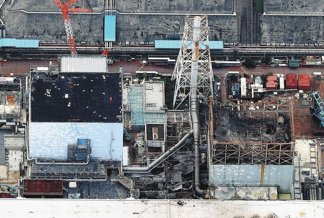 事故発生当初のベントで高濃度に汚染された配管の撤去に向け、準備が進む現場は、水素爆発で最上階が大破した1号機(右側)と爆発を逃れた2号機の間にある=2021年10月11日、福島県大熊町で、本社ヘリ「おおづる」から