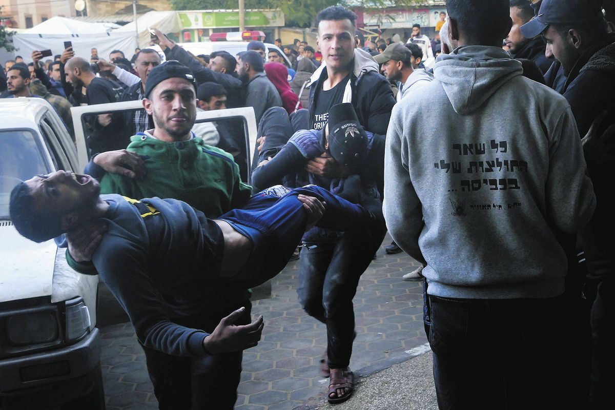 12月24日、イスラエルの爆撃で負傷して搬送されるパレスチナ人男性＝AP