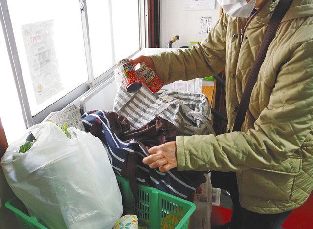 フードバンクで配布された食糧をバッグに詰める女性利用者。「子どもが食べ盛りなので助かる」と話す＝いずれも東京都江戸川区内で