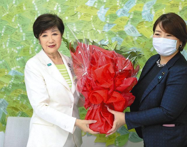 東京都知事選で当選が確実となり、笑顔で花束を受け取る小池百合子さん（左）＝５日、東京都新宿区で