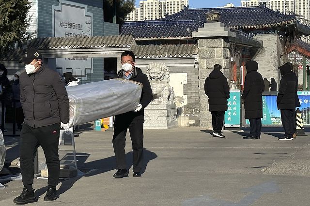 17日、北京の火葬場付近で棺を運ぶ男性ら＝AP