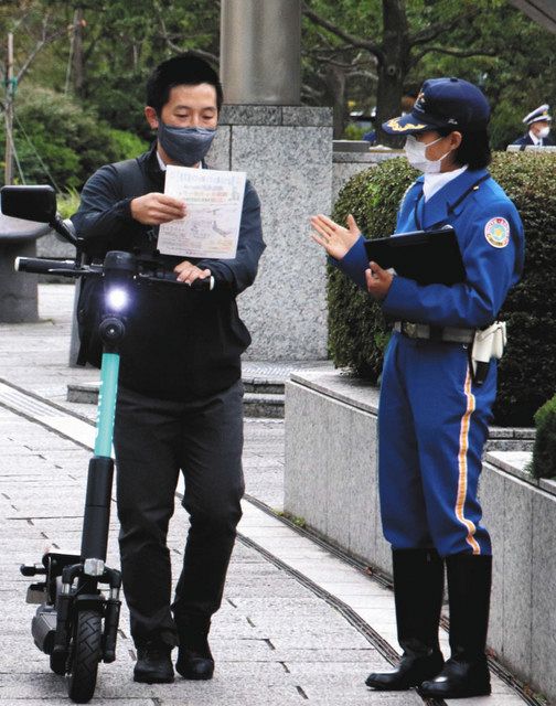 警察官（右）から電動キックボードの乗り方の指導を受ける利用者＝横浜市西区で
