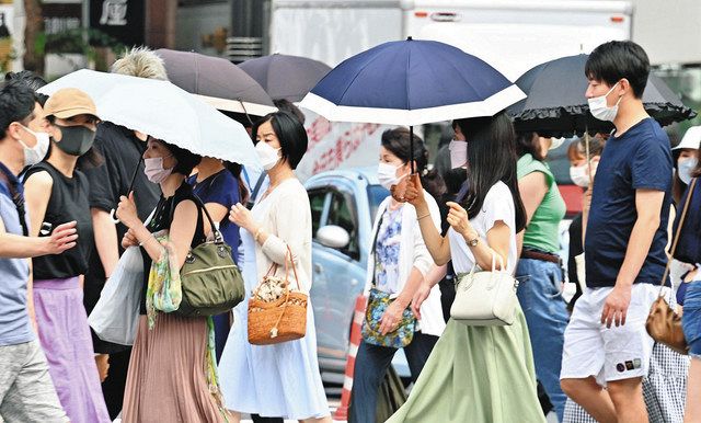 厳しい暑さの中、日傘を差して歩く人たち=東京・銀座で