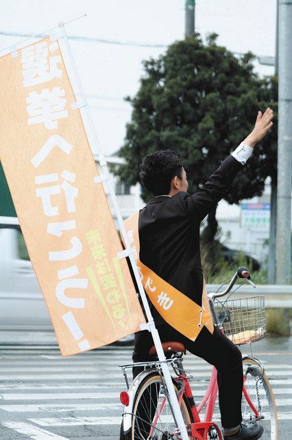 自転車で支持を呼びかける市議選の立候補者＝2019年４月、愛知県内で