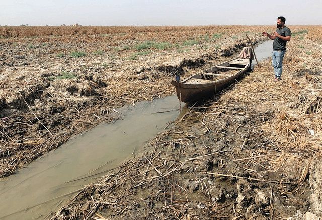 １０月、イラク南部チバイッシュで、干上がった湿地に残された小型ボート。「半年前は湿地だった」と説明するラードさん（蜘手美鶴撮影）