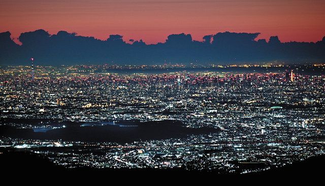 厳寒の雲取山頂から望む夜明け前の都心方面。朝焼けの空と雲のシルエットの下できらめく街あかりがまばゆい。中央左に東京スカイツリー、右に東京タワーが見える＝東京、埼玉都県境の雲取山頂で