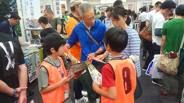 山岳関連イベント「夏山フェスタ」で初めて「ヒルは木から落ちてこない」という新説について発表し、来場者らに説明する子ども研究員たち（手前のオレンジのビブスを着ている2人）＝2018年6月23日、名古屋市のウインクあいちで