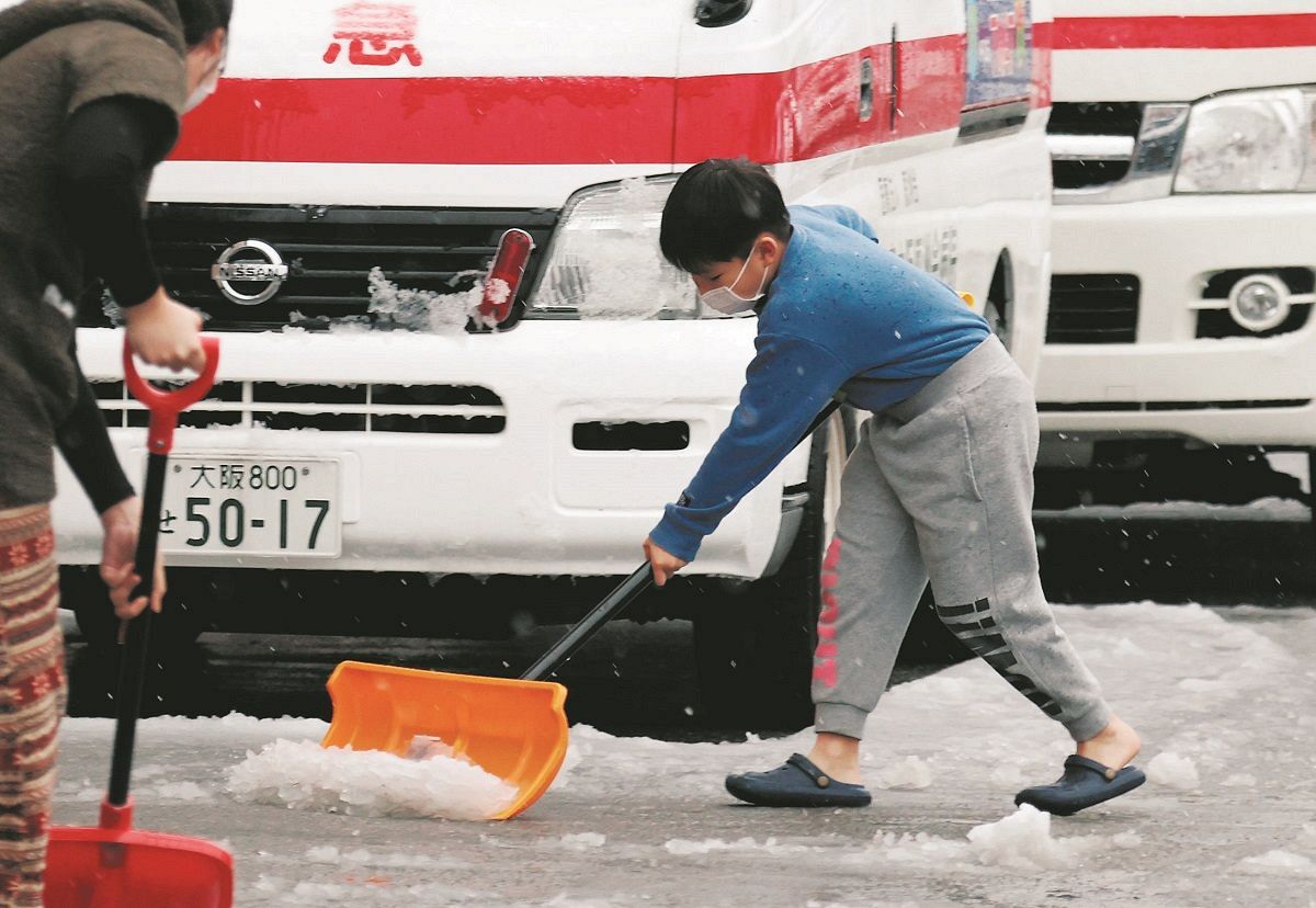 避難所の駐車場で雪かきする子ども＝2024年1月7日、石川県輪島市で