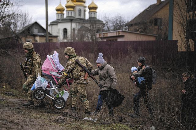 ウクライナの首都キエフ近郊で５日、兵士の支援を受けながら避難する家族＝AP
