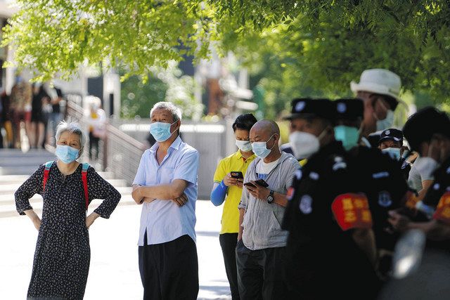 PCR検査のためにマスクをして並ぶ人々＝5日、北京市内で（AP）