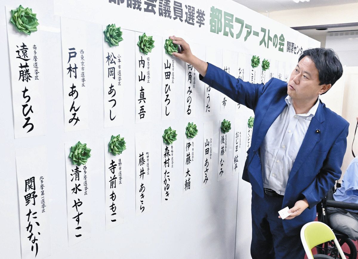 当選確実になった候補者の名札に花を付ける都民ファーストの会・森村隆行代表