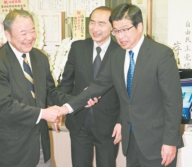 当選を確実にし支援者と握手する山本亨さん（右）